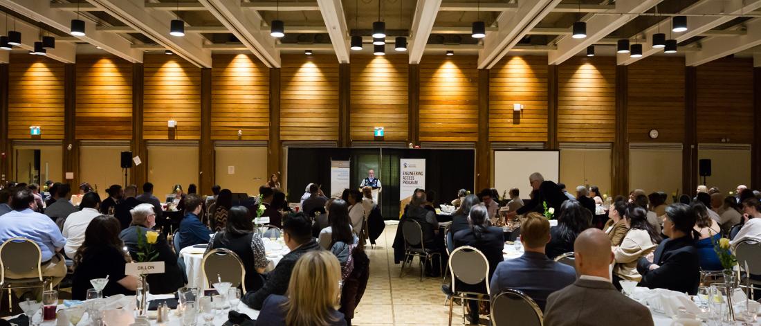 A reception space full of people with guest speaker at podium on one end