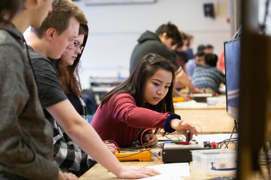 Students gather around a table and work on projects.