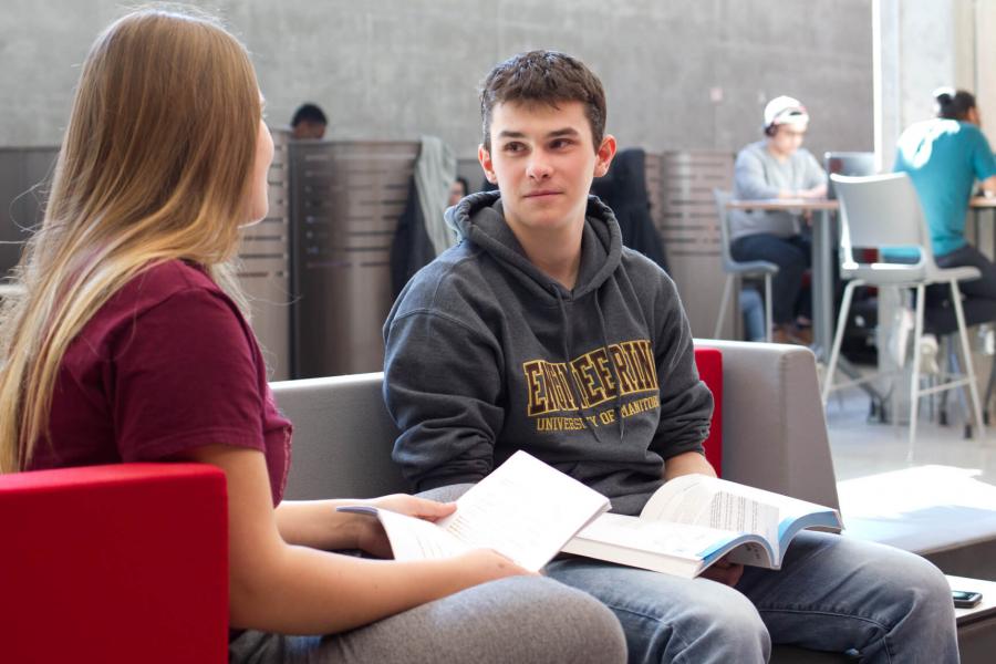 Two engineering students study together in a student lounge area.