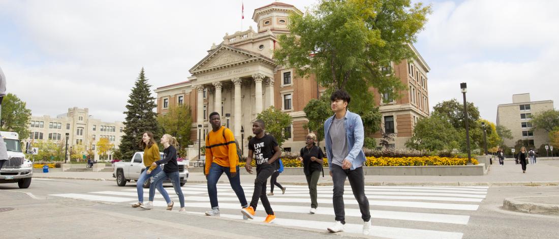 Students walking across the street in front of the UM admin building.