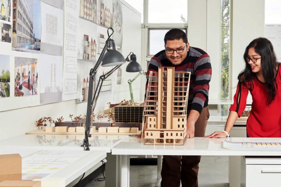 Two students working on a table with a model of a building.