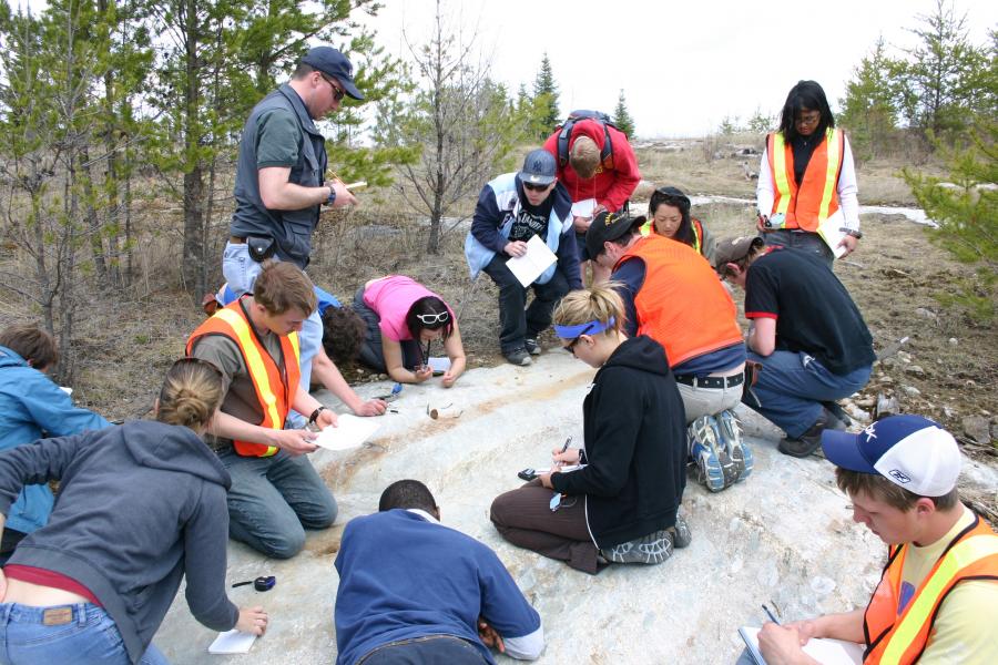 Geology students looking at bedrock surface during start lake field school