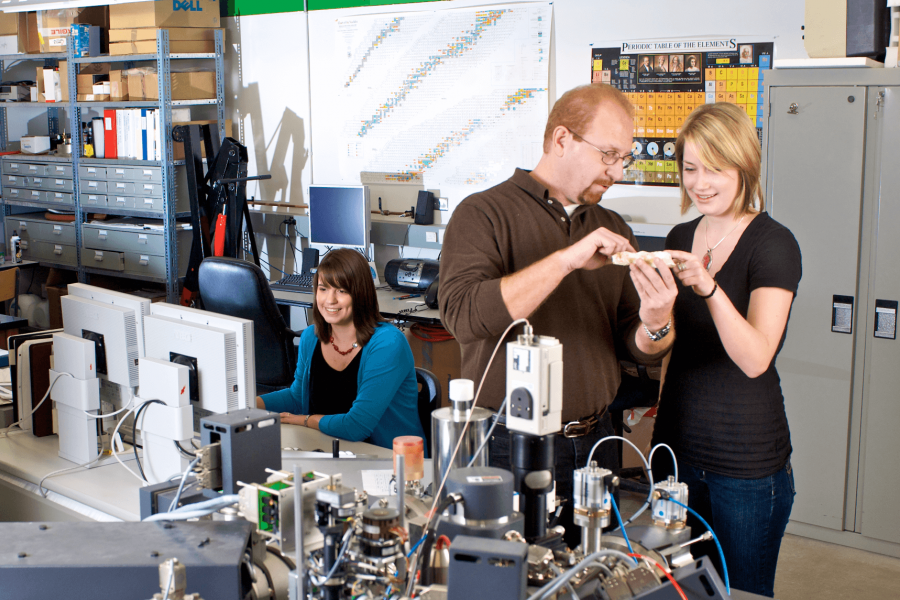 A professor points out details on a vessel he is holding to a student.