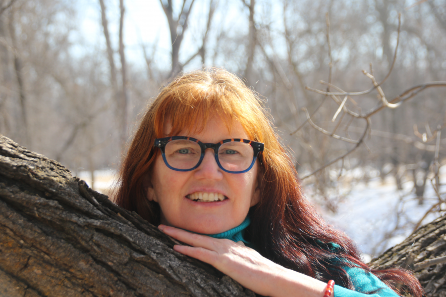 Doctor shirley thompson posing with head resting on a tree outdoors.