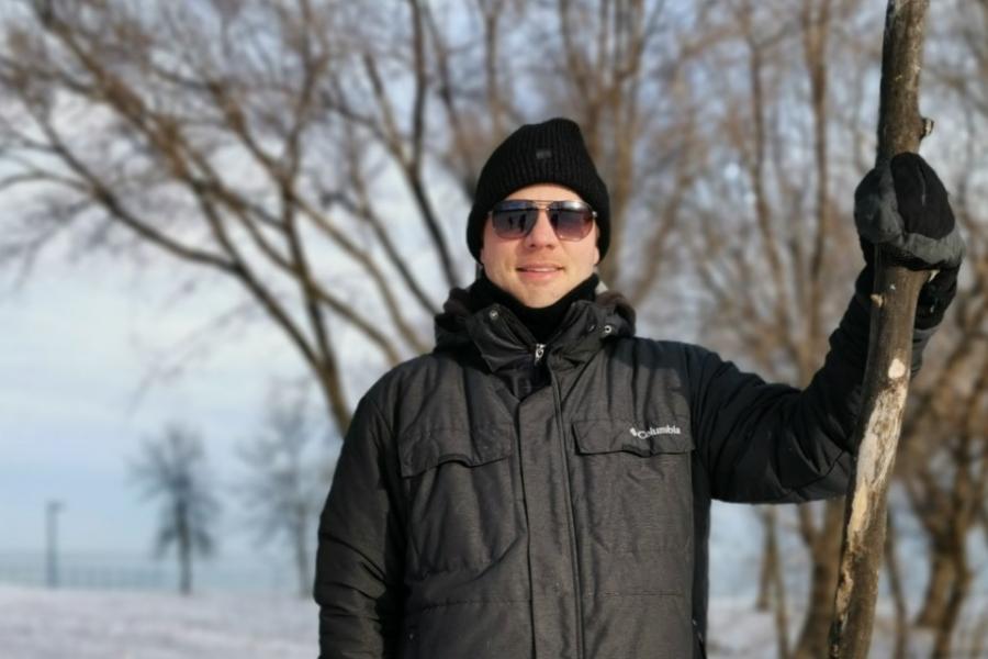 Doctor dustin isleifson posing outside in black parka and hood wearing sunglasses.