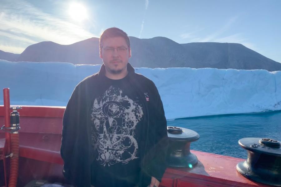 Stephen ciastek in a black shirt standing outside with mountains behind him.