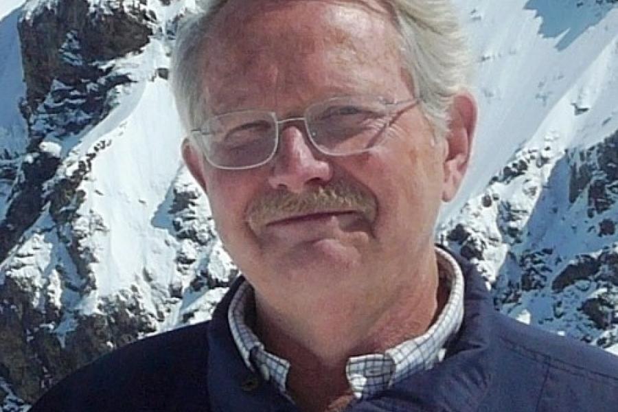 Doctor Jim teller in front of a mountain smiling at camera.