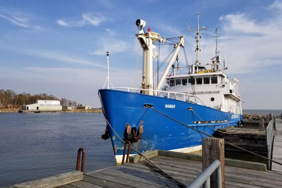 A blue hulled ship docked at a pier.