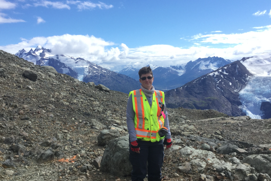 Stefanie brueckner standing in front of mountains wearing a reflective safety vest.