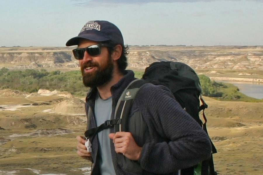 Paul durkin hiking outdoors wearing a backpack hat and sunglasses.