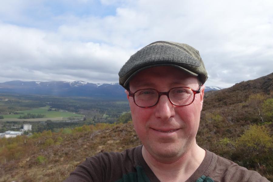 Andrew frederiksen outside looking at camera with hills behind him.