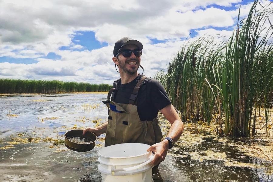 jose luis rodriquez standing in a marsh with a bucket