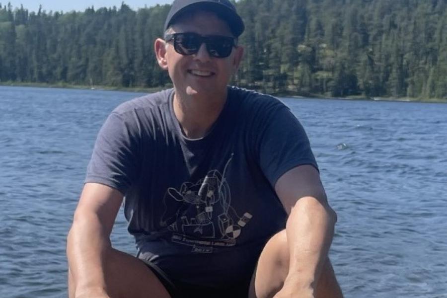 scott higgins in a boat on a lake holding a paddle