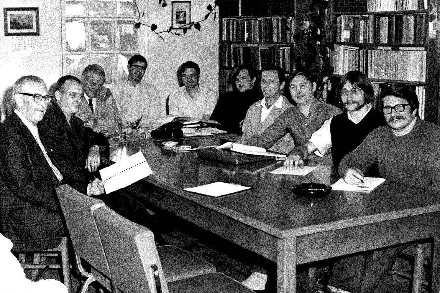 a group photo of people sitting around a desk