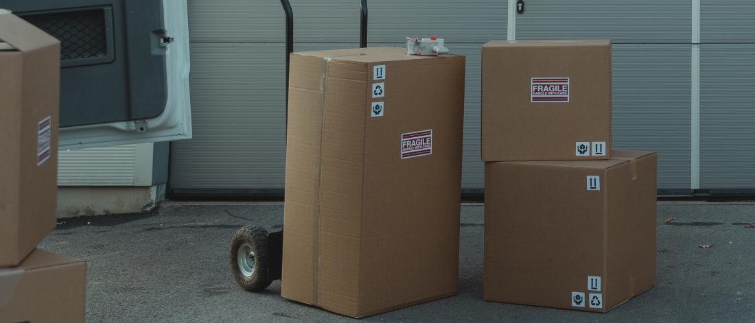 Cardboard boxes on dolly next to van.