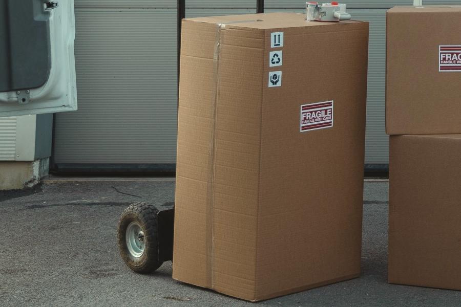 Cardboard boxes on dolly next to van.