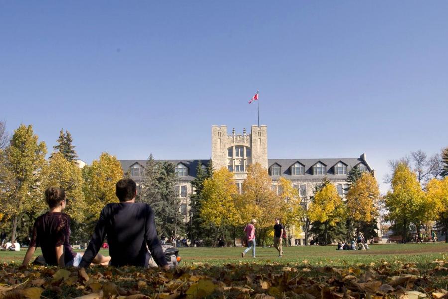 Students sitting outside in the quad surrounded by fall colours. 