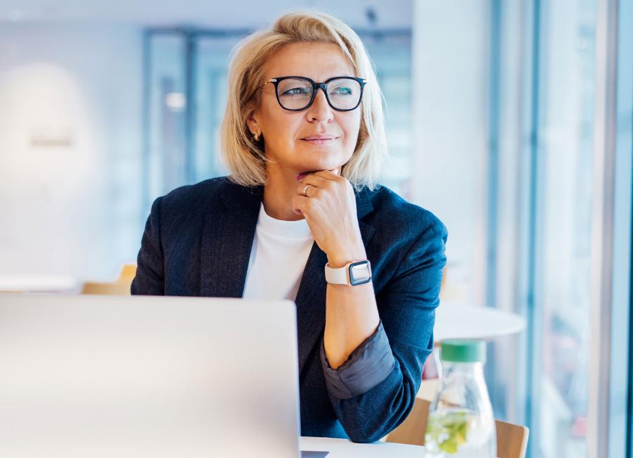Business leader smiling and thinking in front of laptop.
