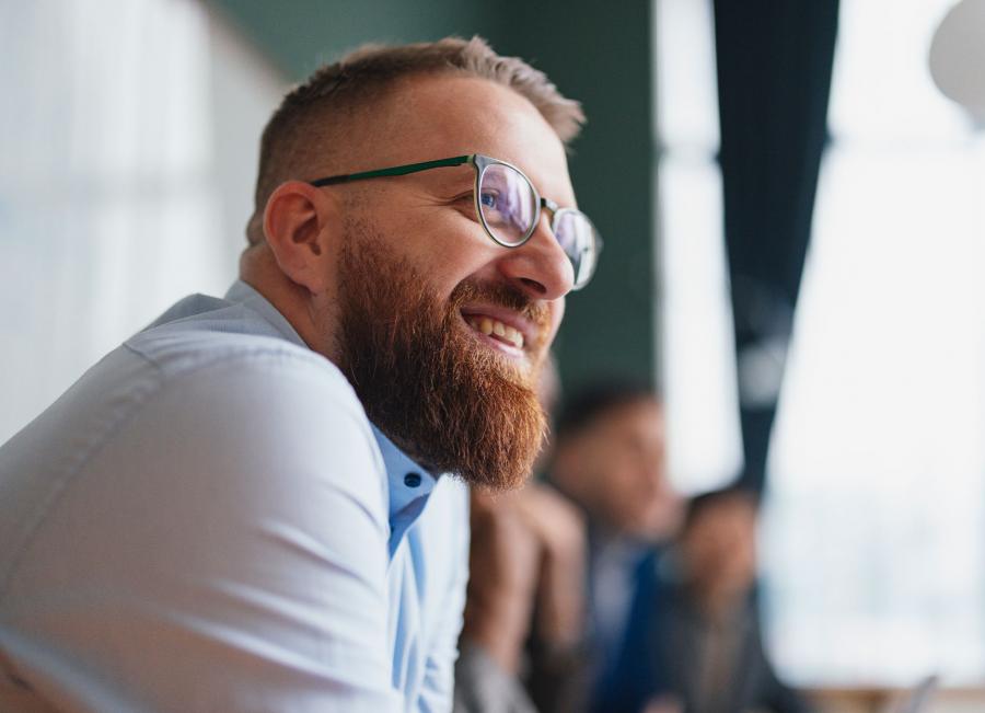 Business professional smiling listening to discussion with colleagues.
