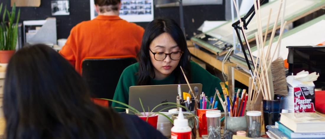 Students sit at their desks working on projects with various supplies and tools.  