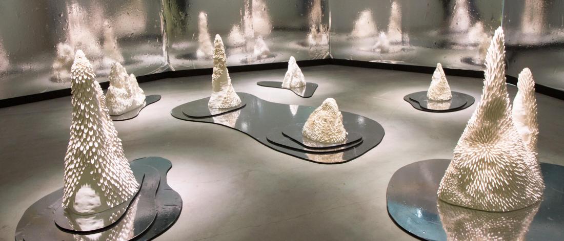 A display of student work featuring various sizes of cone shaped pieces sitting atop metallic silver bases.