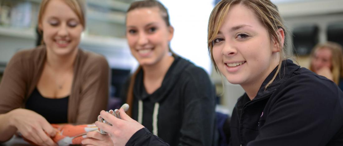 Three students work together in a kinesiology classroom.