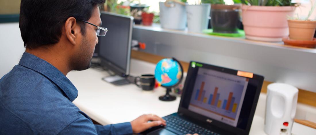 A pharmacist works at a desk on a laptop.