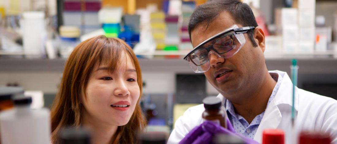 Two pharmacy students look at a bottle in a lab.