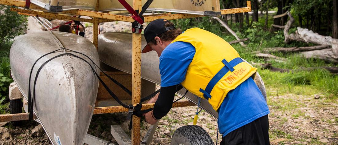 A recreation studies student ties down canoes. 
