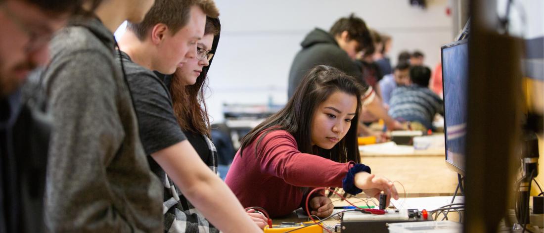 Engineering students work together at a desk in a classroom.