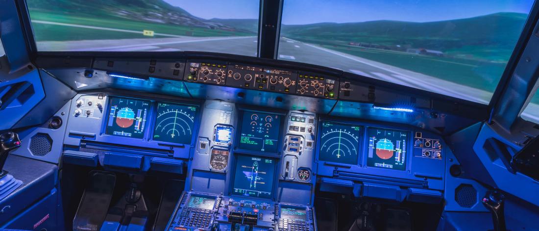 The inside of an airplane cockpit controls as a plane lands on a runway.