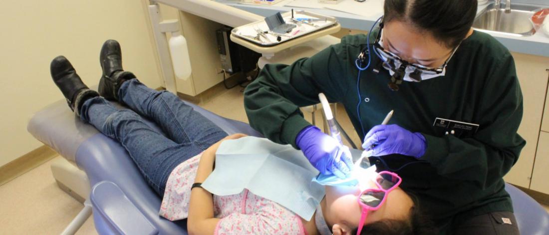 A pediatric dentist works with a patient. 