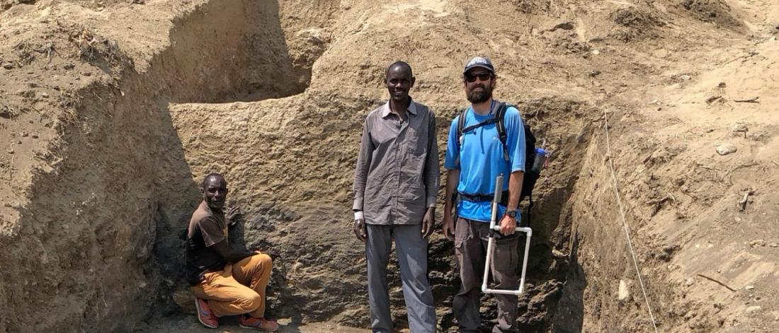 A researcher stands at a work site with his coworkers.