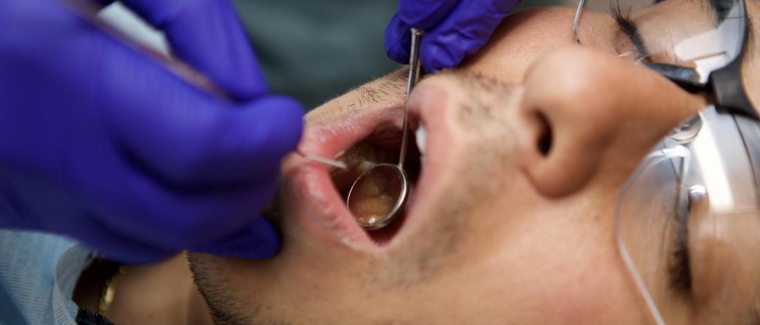 A dentists takes a close look at a patients mouth.