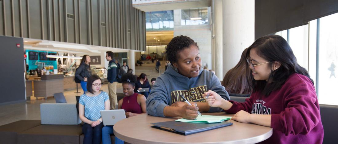 Two students study together at a small table.
