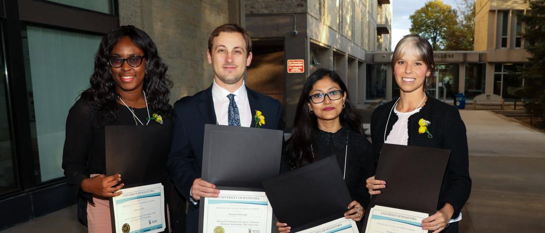 For Master of Laws students stand side by side holding certificates in front of them.