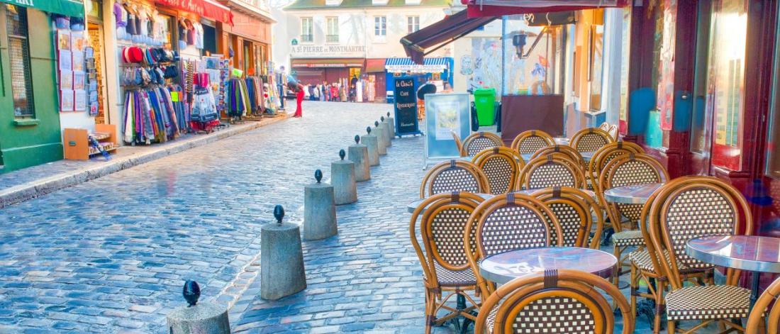 Cobblestone street with shops and outdoor cafe in France.