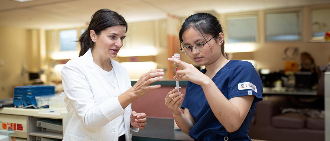 Instructor coaches a student preparing a syringe.