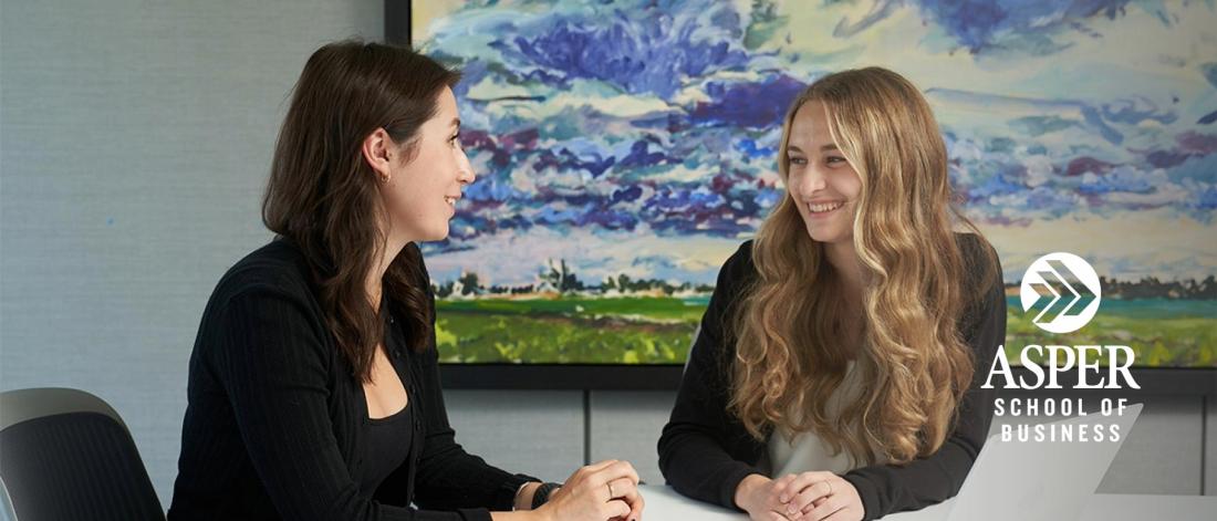Image of two female students discussing projects in a meeting room.
