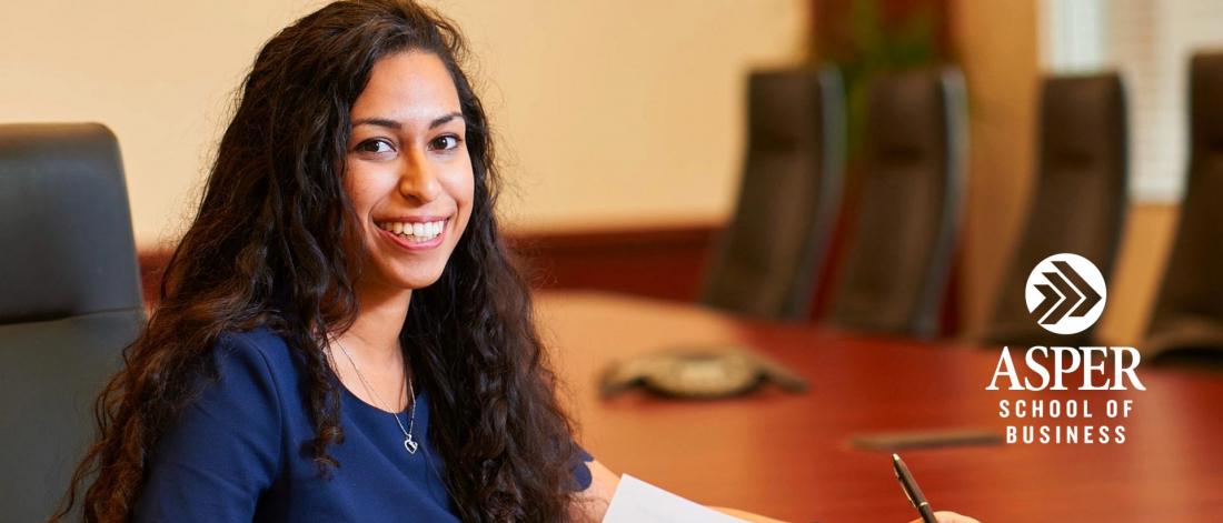 Image of a female student taking notes in a boardroom.