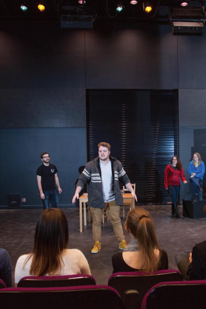 Students perform on stage while an audience watches. 