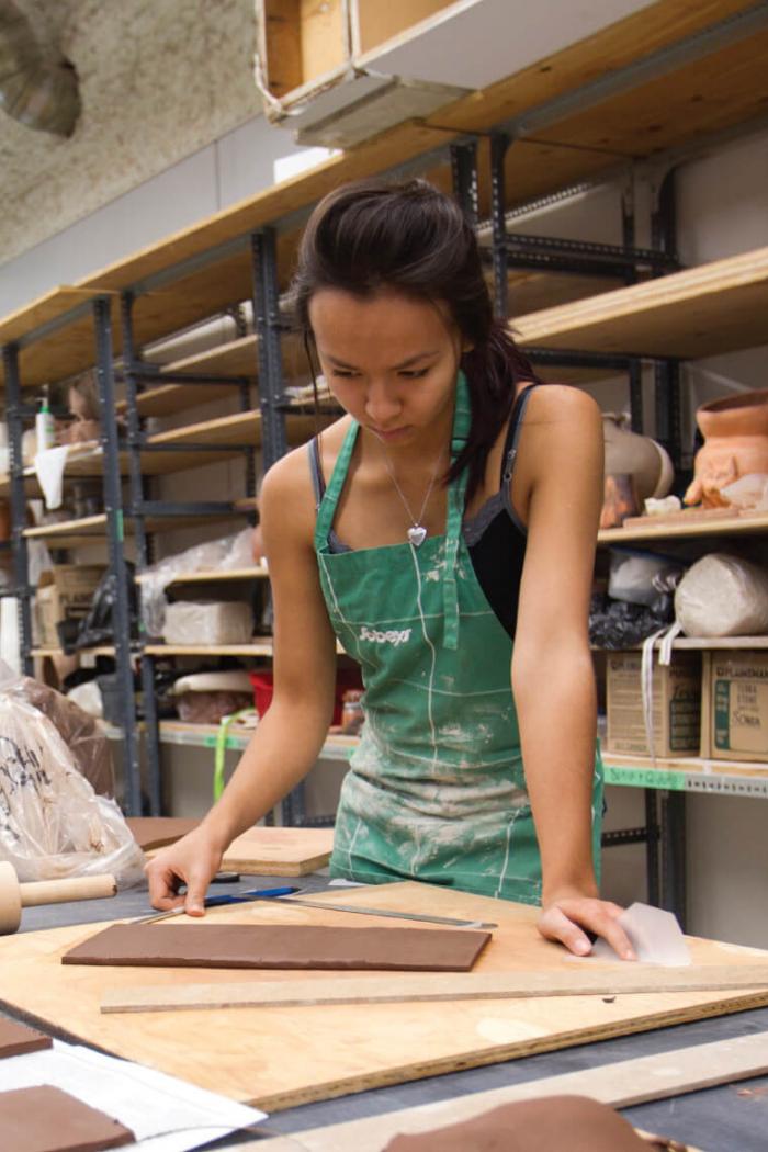 A school of art student works at a bench on a project.