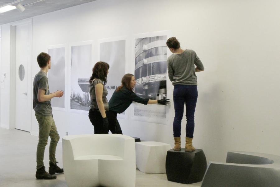 Four students work together to install a photography project for display.