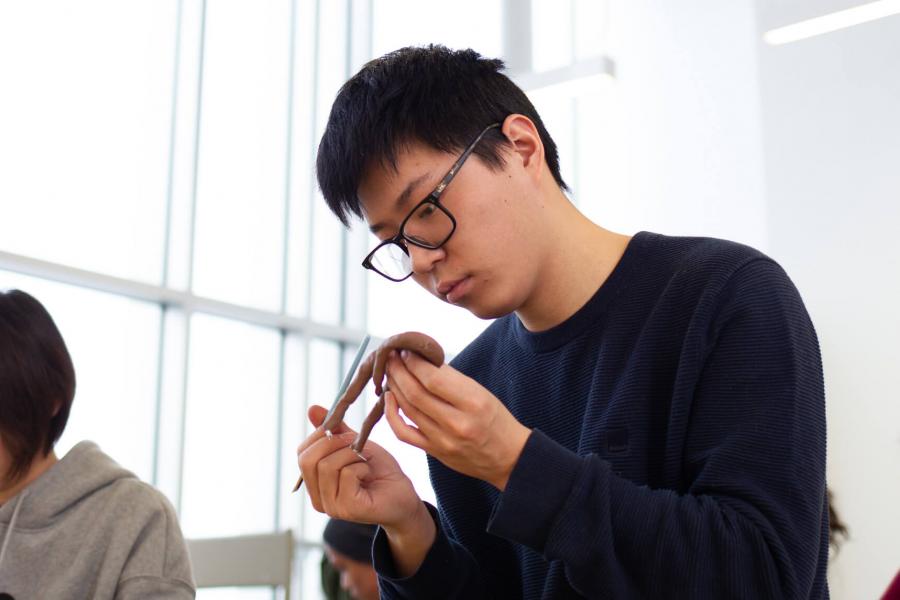 A student works intently on a small sculpture project. 