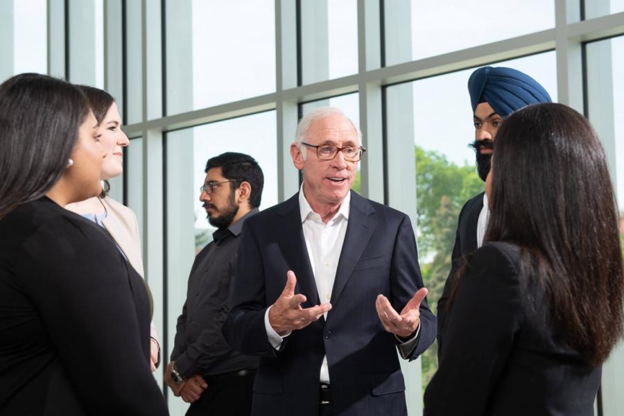 Asper students speak casually with Stu Clark during an event.