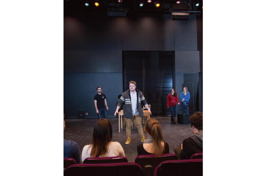 Students perform on stage while an audience watches. 