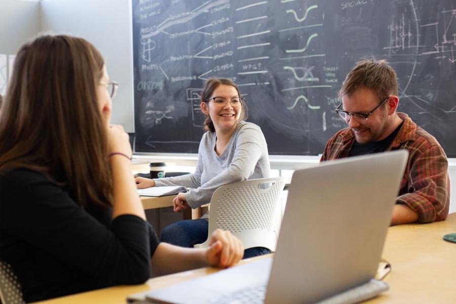 Smiling students talking in a classroom.