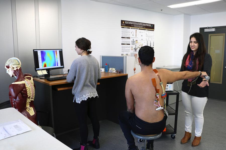 Two students use sensors to take measurements of a test patient.