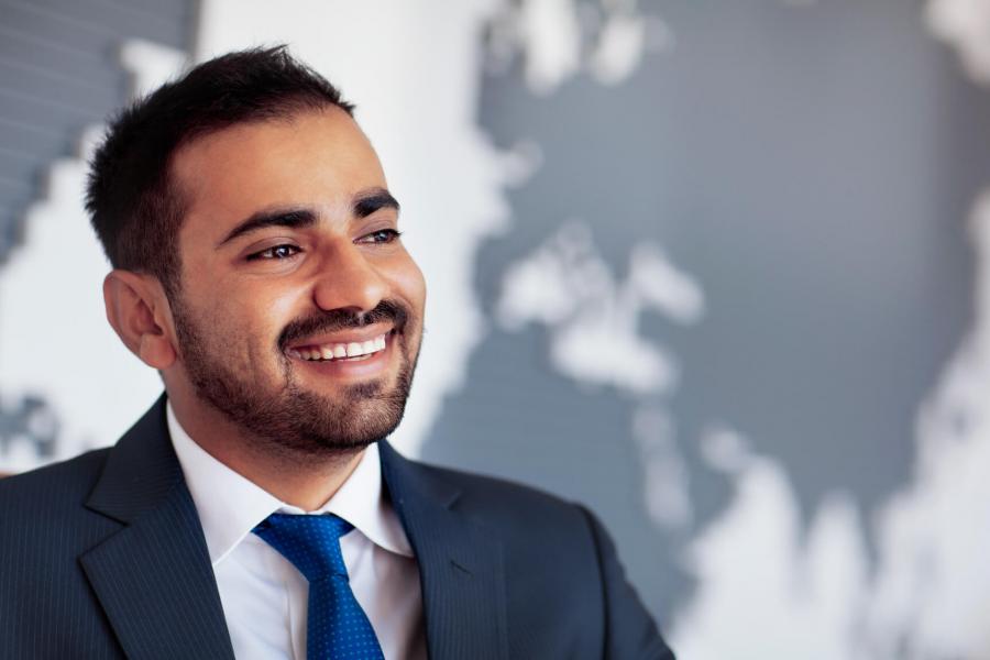 A man smiles, a silhouette of the globe is behind him.