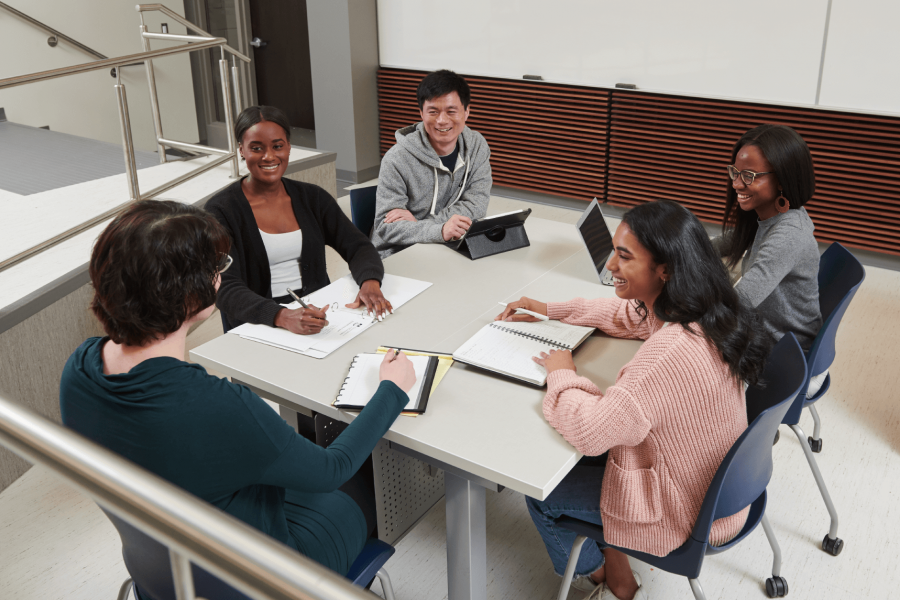 Students seated around a square table in a classroom at the Drake Centre.